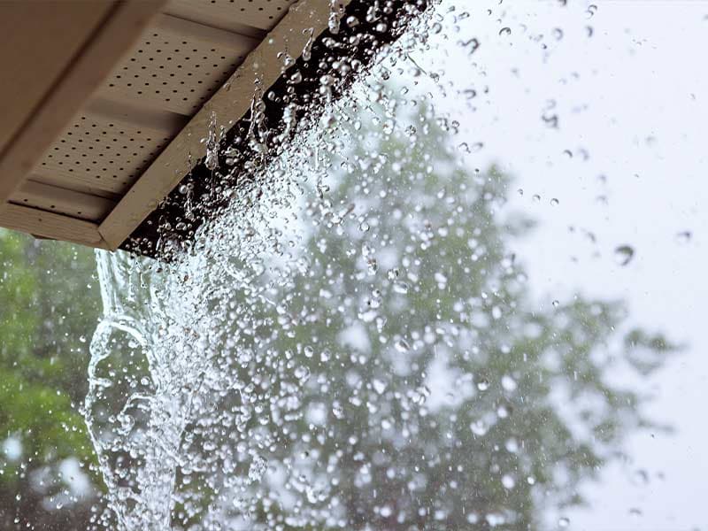 Heavy rain pouring off a roof edge and gutter